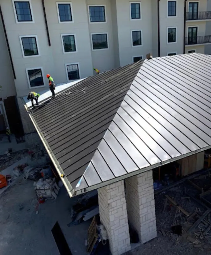 Crew installing standing seam metal roof panels on a commercial project in Hayden